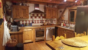 A compact kitchen with wooden cabinets, a Bosch refrigerator, and a tiled backsplash.