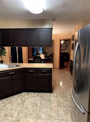Enjoy cooking in this well-equipped kitchen with a stainless steel refrigerator, sink, and countertop space.
