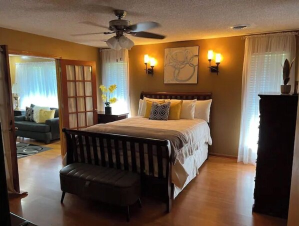 Relax in this serene bedroom with a large bed, wall-mounted lamps, and a ceiling fan.