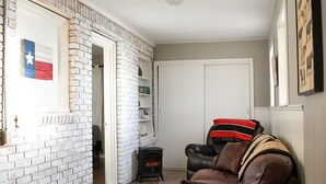 A living room with a brick wall, a fireplace, a leather sofa, and a small black heater.