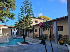 A courtyard with a swimming pool, a fountain, and a large tree. - Pousada Praia de Ponta Negra (Natal)