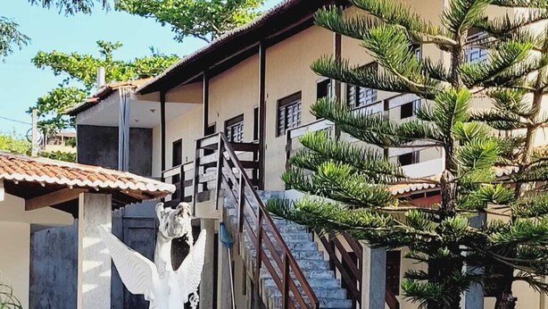 Uma área de piscina com uma estátua, escadaria e um edifício com telhado telhado.