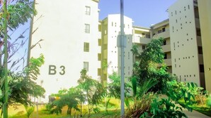 Un moderno edificio de apartamentos con balcones, rodeado de exuberante vegetación.