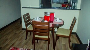 Un comedor con una mesa redonda, cuatro sillas de madera y una ventana sobre la mesa.