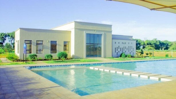 Un edificio moderno con piscina, ventanas amplias y un patio cubierto.