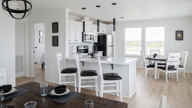 A modern kitchen with white cabinetry, a central island, and pendant lighting.