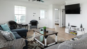 A modern living room with a sectional sofa, a coffee table, and a TV mounted on the wall.