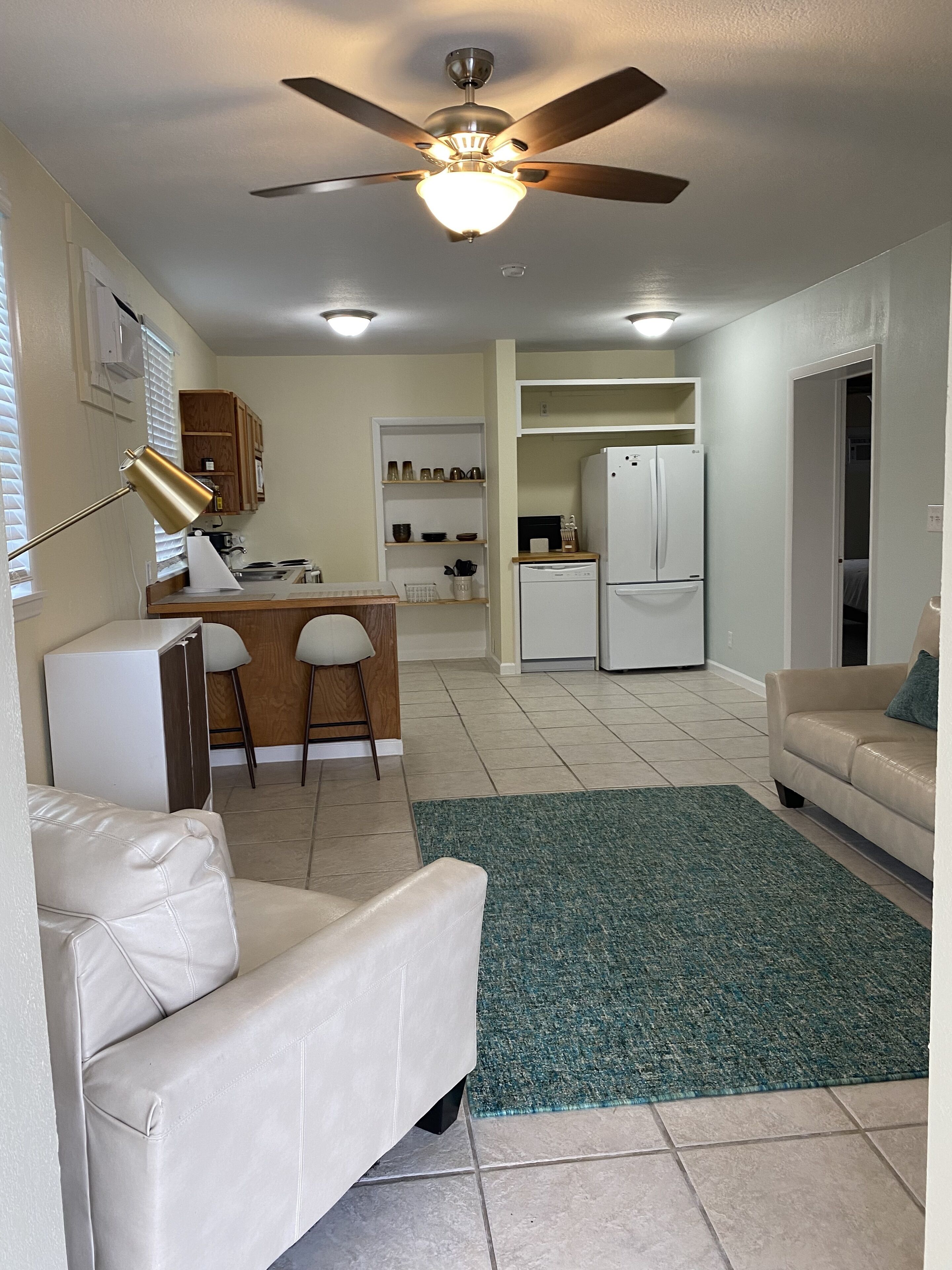 A compact living space with a kitchenette, a dining area, and a seating area with a sofa and a chair.