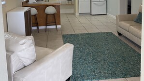 A compact living space with a kitchenette, a dining area, and a seating area with a sofa and a chair.