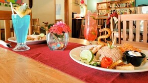 A dining table with a plate of food, two drinks, and a vase with flowers.