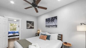 A bedroom with a bed, a ceiling fan, a nightstand, a lamp, and a window with a view of the outdoors. - Unit 2 - B Ave Bungalows · Beachside 1/1, 5-10 Min Walk to Coronado Beach! (Coronado)
