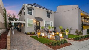 A modern two-story house with a covered porch, solar panels, and a well-maintained garden with potted plants and a fountain. - Unit 2 - B Ave Bungalows · Beachside 1/1, 5-10 Min Walk to Coronado Beach! (Coronado)