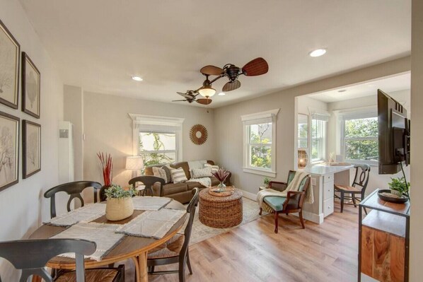 A spacious living area with a dining table, chairs, a sofa, and a ceiling fan.