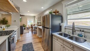 Una cocina moderna con electrodomésticos de acero inoxidable, un refrigerador grande y un ventanal que proporciona luz natural.