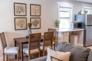 A modern kitchen with a microwave, refrigerator, and a dining area with a table and chairs.