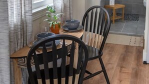 A dining area with a wooden table, two black chairs, a bowl, and a potted plant. - Back Building A-C - B Ave Bungalows · All 3 Studios, 5-10 Min Walk to Coronado Beach! (Coronado)