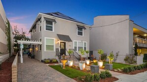 Ein modernes, zweistöckiges Haus mit überdachter Terrasse, Solaranlage und einem gut beleuchteten Garten.