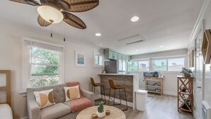 A modern living room with a sofa, a round coffee table, and a dining area with two bar stools. - Unit C - B Ave Bungalows · Surf Shack Studio, 5 Min Walk to Coronado Beach! (Coronado)