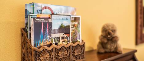 A wooden tray holding travel brochures and a small figurine on a wooden table.