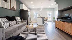 Un salon moderne avec un canapé, une table basse et un téléviseur.