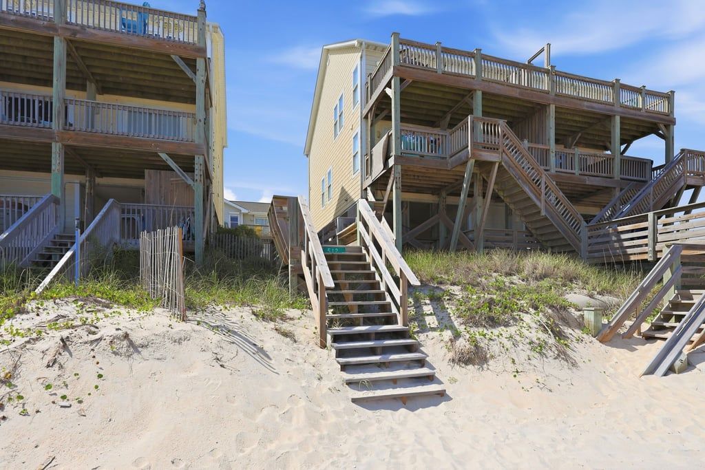 A beachfront building with multiple balconies and wooden staircases leading to the beach.