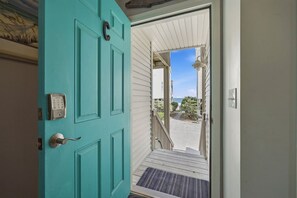 A turquoise door with a keypad lock, a small porch, and a view of the outside.