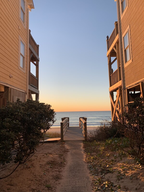 A wooden pathway leading to a beach with a clear view of the ocean.