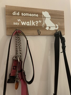 A wooden sign with a dog silhouette and the text "did someone say 'walk'?" mounted on a wall, with two dog leashes hanging below. - Not quite ocean front, but almost! Just a few steps to the sand! Pet friendly. (Surf City)