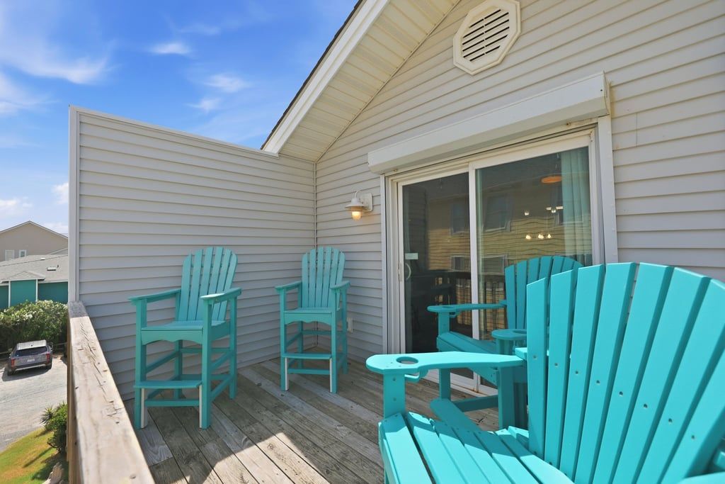 A covered outdoor area with wooden deck, two chairs, and a table.