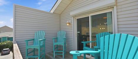 A covered outdoor area with wooden deck, two chairs, and a table.