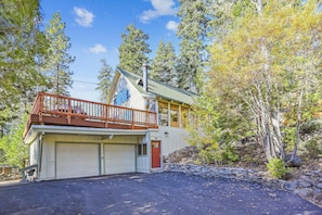 A two-story house with a garage, a balcony, and a stone wall.