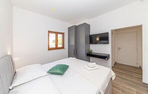 Relax in a serene space with a comfortable bed, flat-screen TV, and bench.