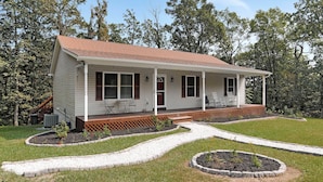 A single-story house with a porch, a small garden, and a pathway leading to the entrance.