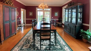 A dining room with a wooden table, chairs, a chandelier, and a patterned rug. - Marsa's Place-Marsh/Creek/Ocean Views; Easy Beach Access;Dogs Welcome (Edisto Island)