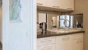 Une cuisine moderne avec des meubles blancs, un plan de travail foncé et des appareils électroménagers en acier inoxydable.