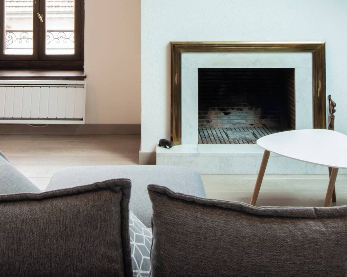 A living room with a fireplace, a white table, and grey sofas.