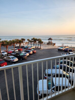 A parking area with multiple cars, a beach view, and a gazebo structure. - OCEAN FRONT STUDIO with 2 full beds & kitchenette (Daytona Beach)