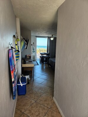 A hallway with tiled flooring leading to a balcony with a view of the ocean. - OCEAN FRONT STUDIO with 2 full beds & kitchenette (Daytona Beach)