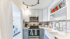 Una cocina moderna con gabinetes blancos, un microondas de acero inoxidable y un horno doble.