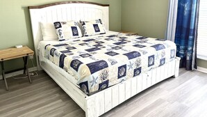 Un dormitorio con cama, mesita de noche y una pared con tres cuadros.