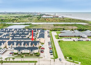 Vista aérea de uma área residencial com vários edifícios de apartamentos, um estacionamento e uma orla marítima.
