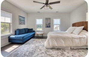 Ein Schlafzimmer mit einem Bett, einem blauen Sofa, einem kleinen runden Tisch und einem Deckenventilator.