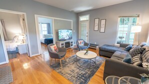 Un salon moderne avec un canapé, des fauteuils, une table basse et un téléviseur.
