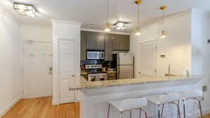 Una cocina moderna con encimeras de granito, electrodomésticos de acero inoxidable e iluminación colgante.