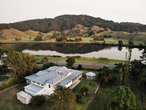 Ein Haus mit großer Garage und überdachter Terrasse, umgeben von einem See und hügeliger Landschaft.