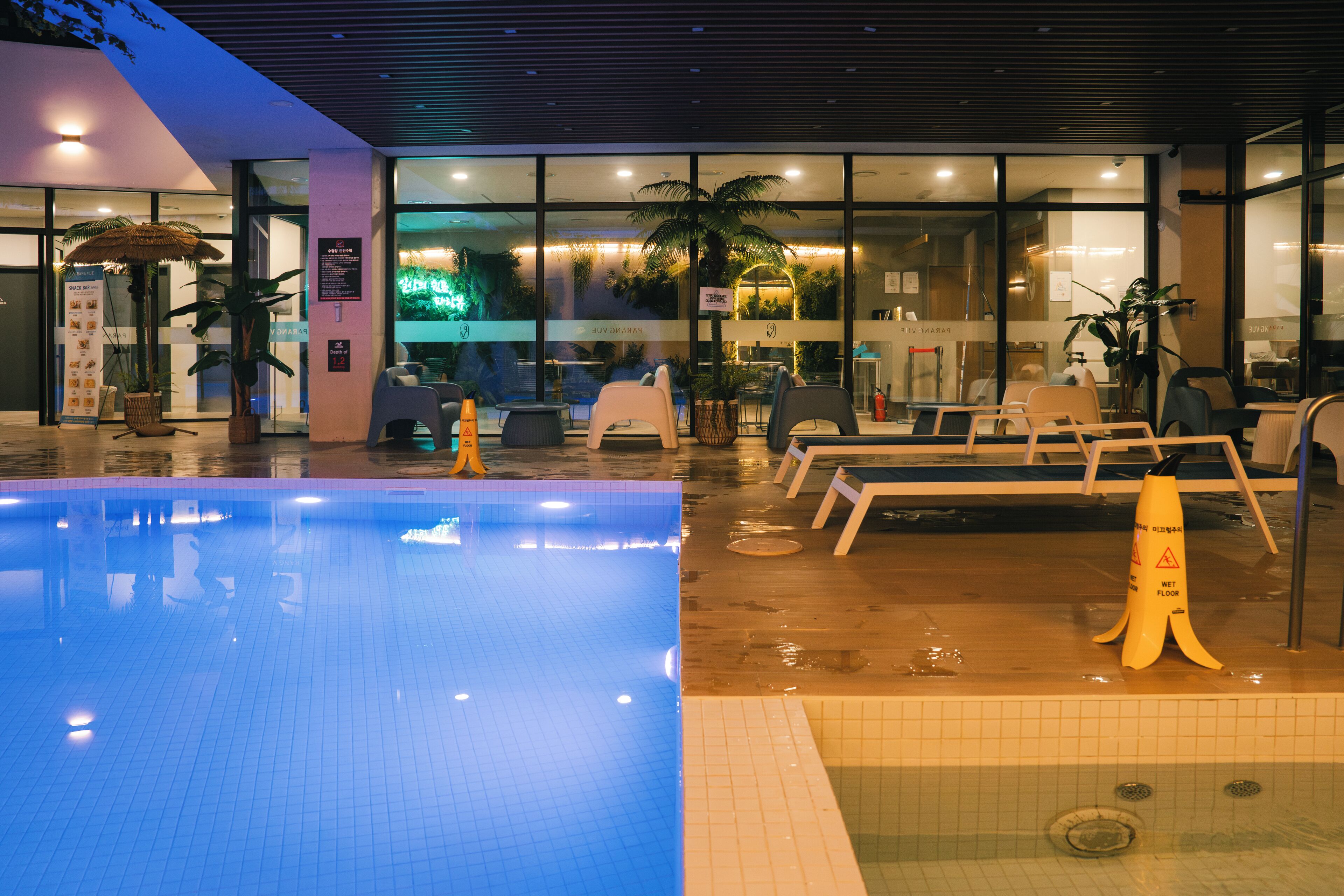 Zona de piscina de hotel con sillones de descanso y señal de piso mojado.