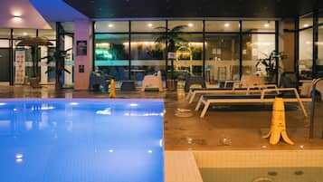 Zona de piscina de hotel con sillones de descanso y señal de piso mojado.
