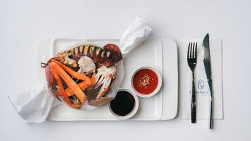 Bandeja con un cangrejo, dos salsas para mojar y un juego de cubiertos sobre una bandeja blanca.