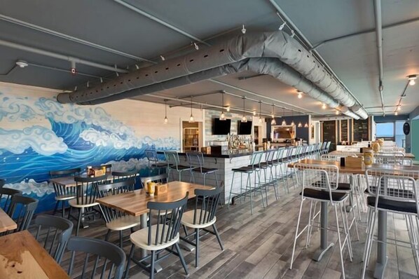 A restaurant with a wave mural, bar area, and modern seating.