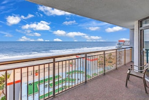 A balcony with a view of the ocean and a pool area.